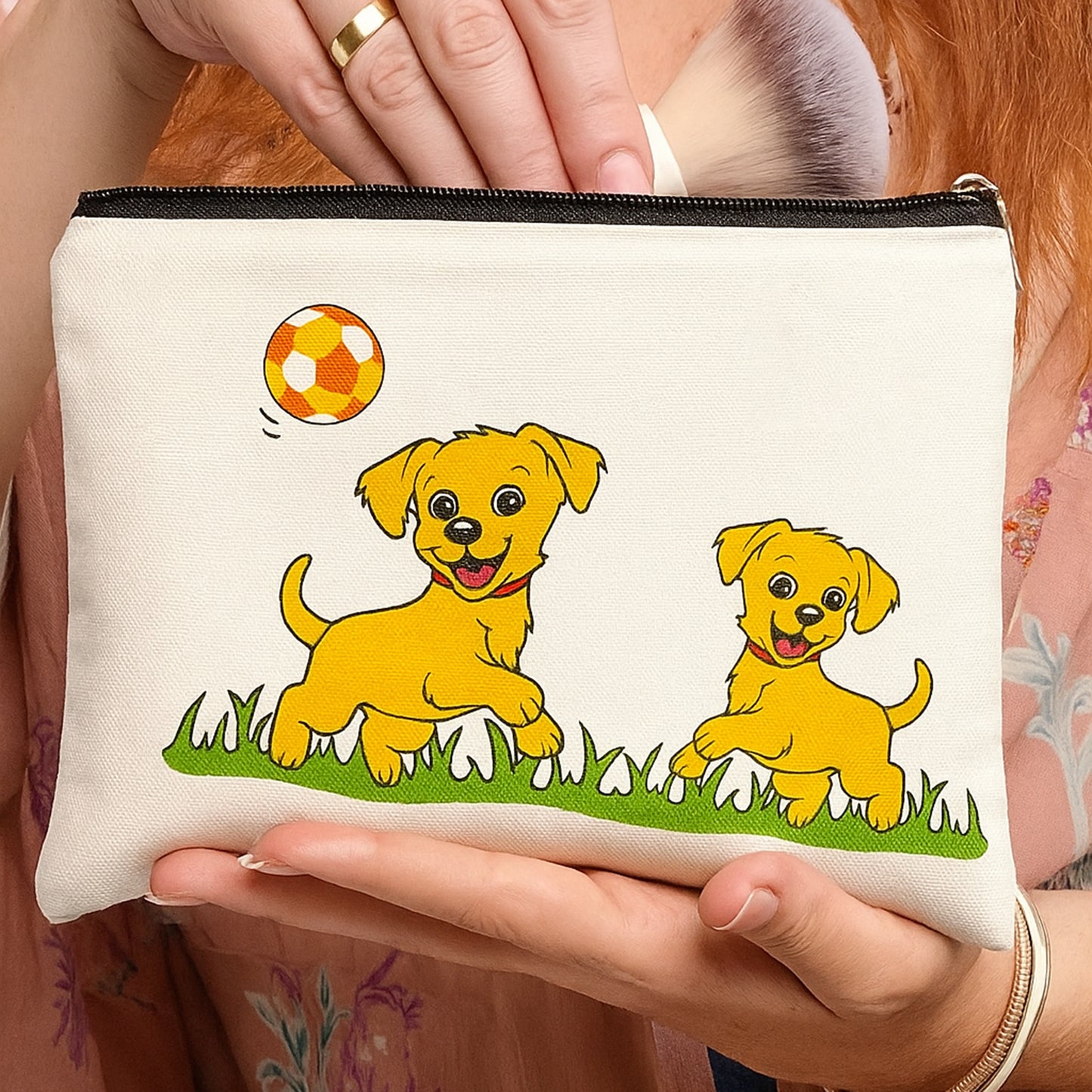 Small pouch with cartoon dogs and a ball design held by a person.