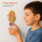 Child holding a colorful seahorse magnet on a white wall with text about fridge magnets.