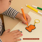 Child coloring a keychain with an orange marker on a beige surface.