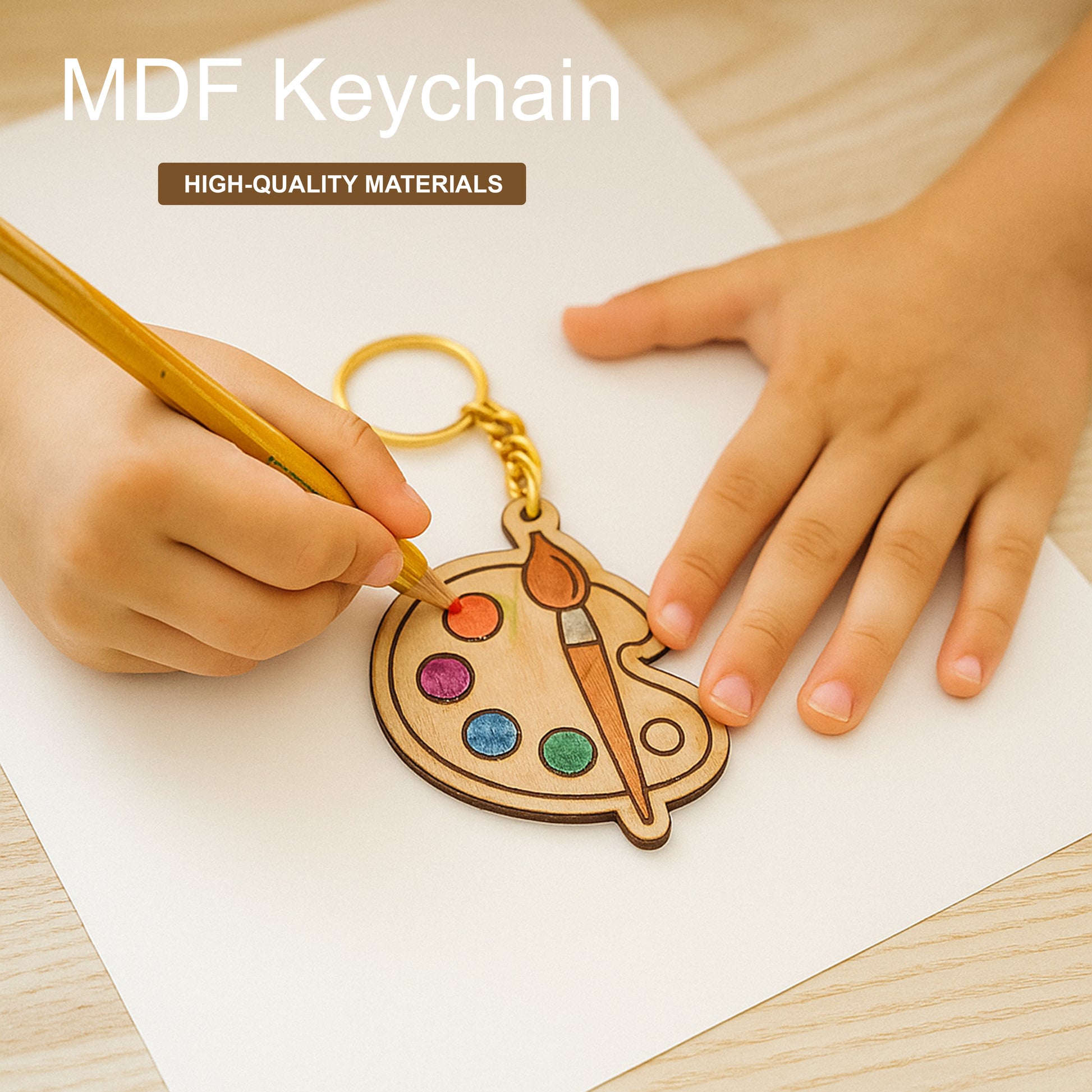 MDF keychain shaped like a paint palette with colorful dots and a brush, held by hands on a wooden surface.