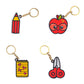 Four keychains shaped like a pencil, apple with glasses, notebook, and scissors on a white background.