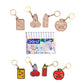 Set of keychains shaped like stationery items with a pack of DOMS watercolor pens in the center.