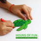 Child's hands coloring a green turtle drawing with red marker on a white background.